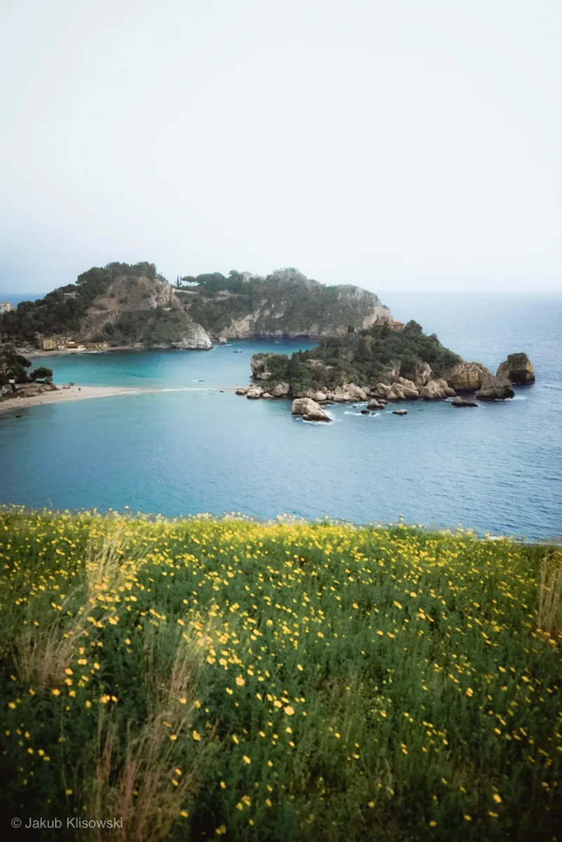 Fotografia podróżnicza — Isola Bella na Sycylii, żółte kwiaty na pierwszym planie, błękitne morze, Jakub Klisowski JVISION